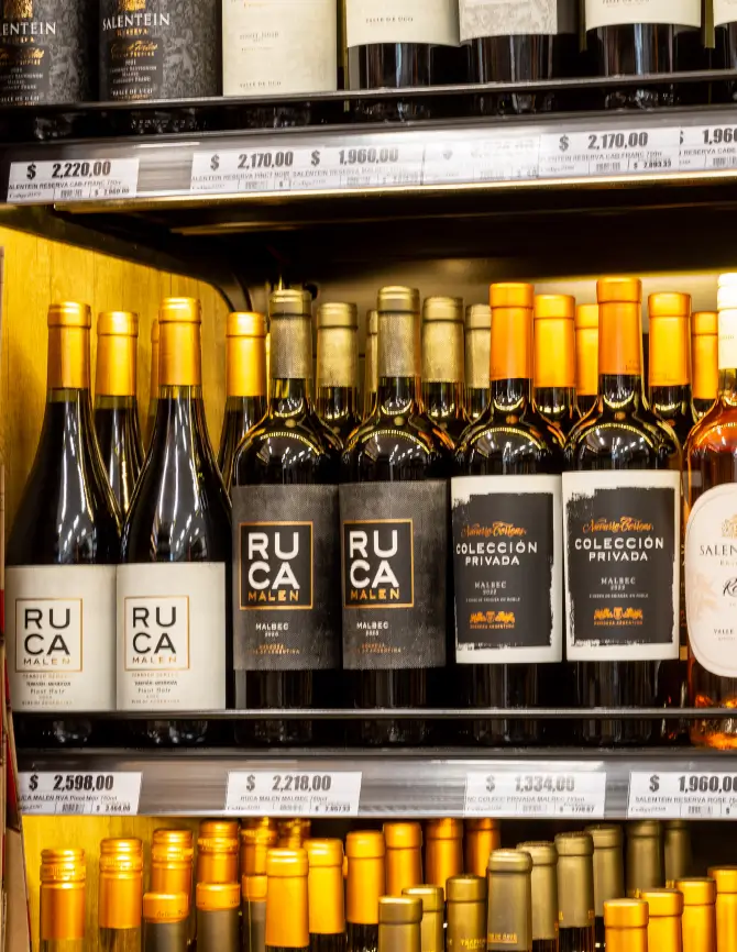Lineal de vinos en góndolas metálicas con etiquetas y portaprecios en supermercado