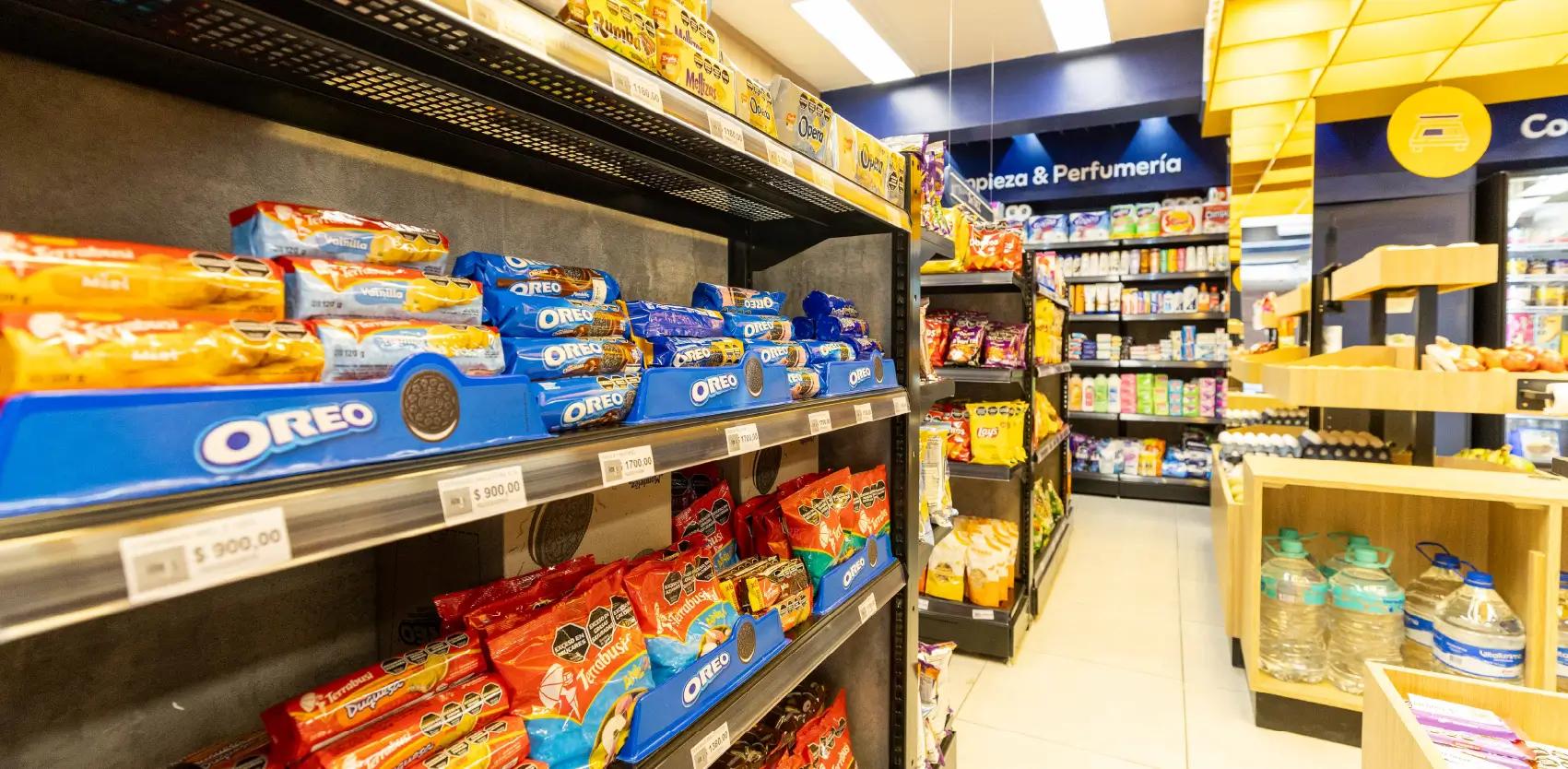 Góndolas de supermercado con exhibición de snacks y sector de perfumería organizado por categorías
