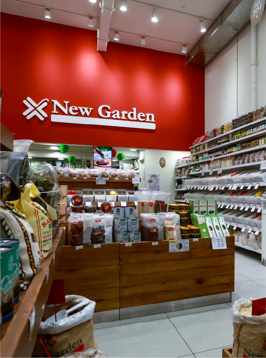 Vista interior de tienda New Garden con góndolas de madera y exhibición de productos naturales organizada por categorías