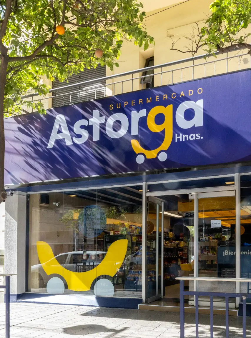 Fachada de supermercado Astorga Hnas. con cartel azul y amarillo en la entrada